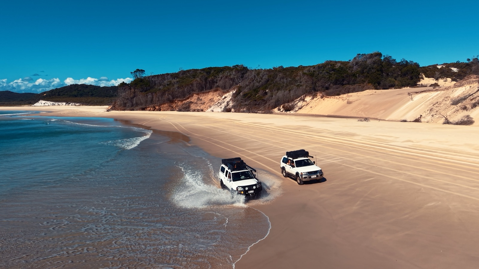 Two Campfire Crew vehicles travelling along Moreton Island beach