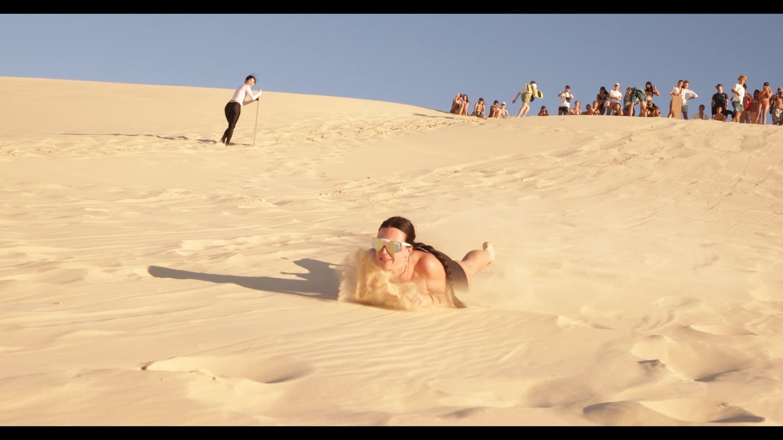 A traveller sandboarding down a Moreton Island dune